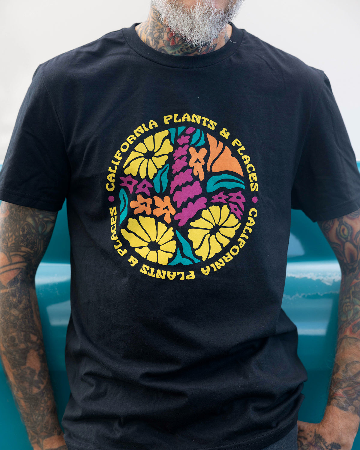 Man wearing the California Tree Oaks T-shirt, featuring a bold nature-inspired design with orange poppies and wildflowers