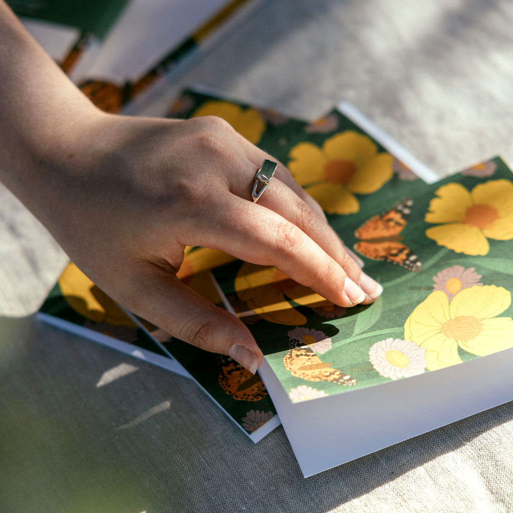 Hand with a ring opening floral card with butterflies and leaves