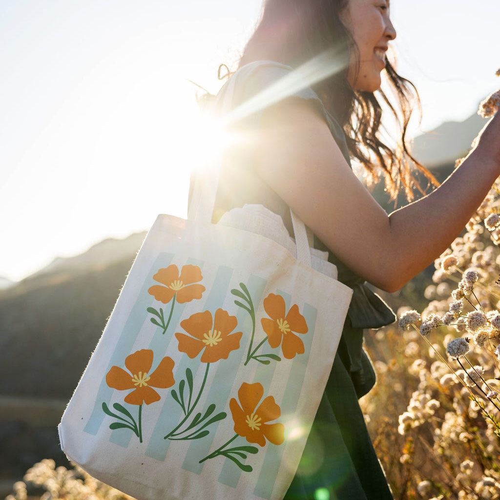 Woman holding a tote bag with floral design with california buckwheat