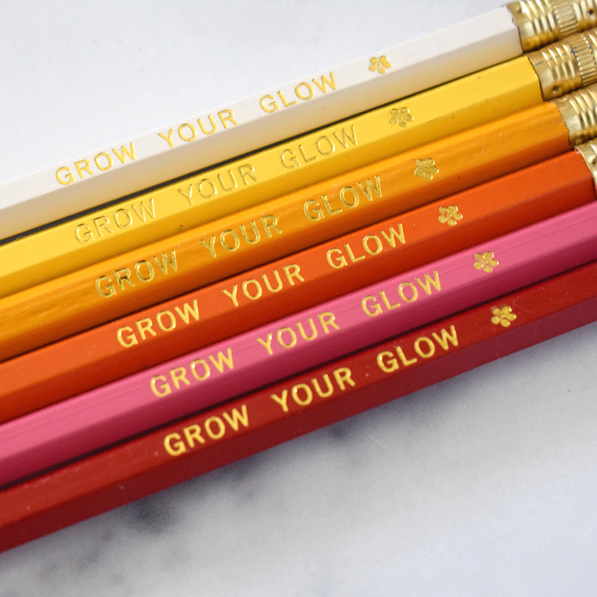 Close-up view of pencils stamped with “Grow Your Glow” in gold foil