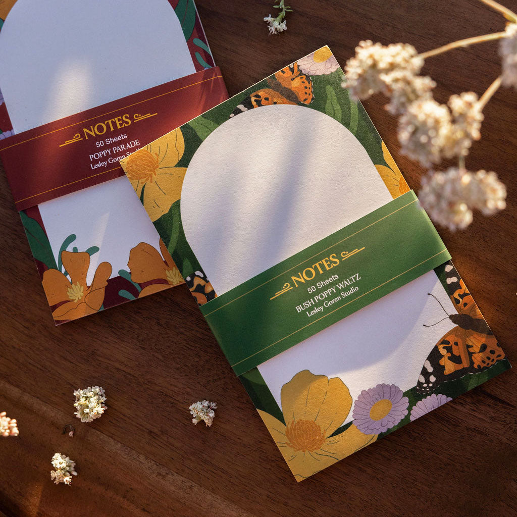 green notepad with floral designs on a wooden surface with dried flowers.