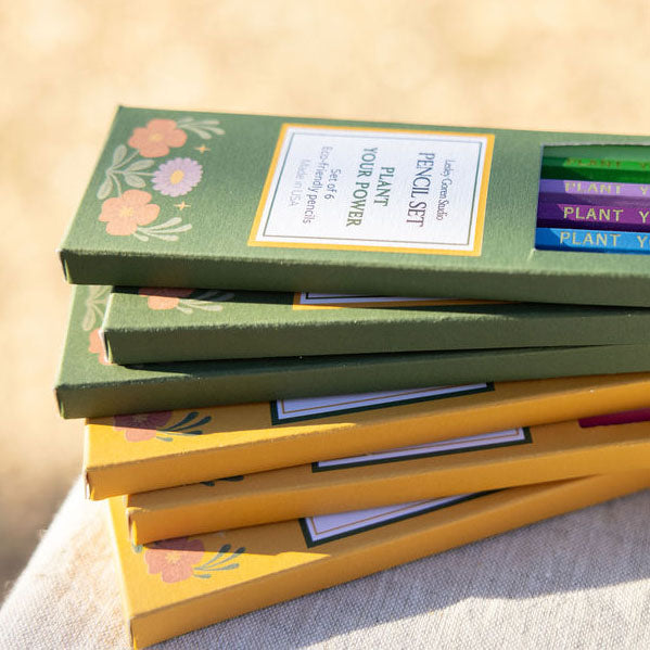 Set of colored pencils in green and yellow boxes with floral designs.