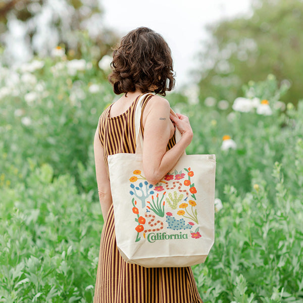 Model holds the Desert Flora Tote featuring vibrant illustrations of California’s native desert flowers on cotton fabric.